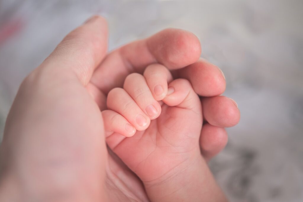A parent holding a young child hand in a custody case